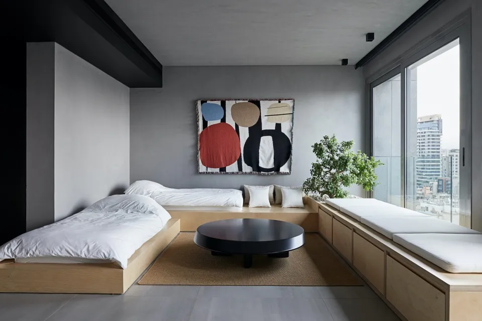 Modern living room with concrete walls, dark flooring, and minimalist furniture.