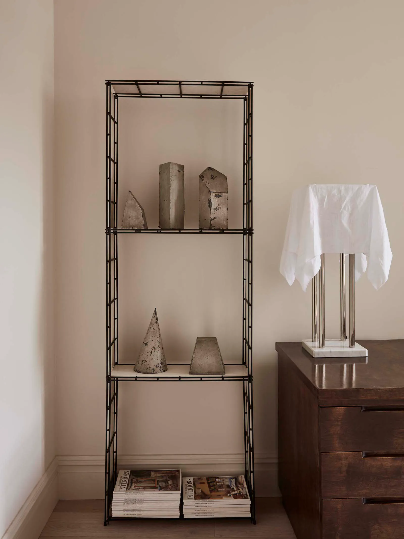 A minimalist metal shelving unit displaying abstract sculptures.