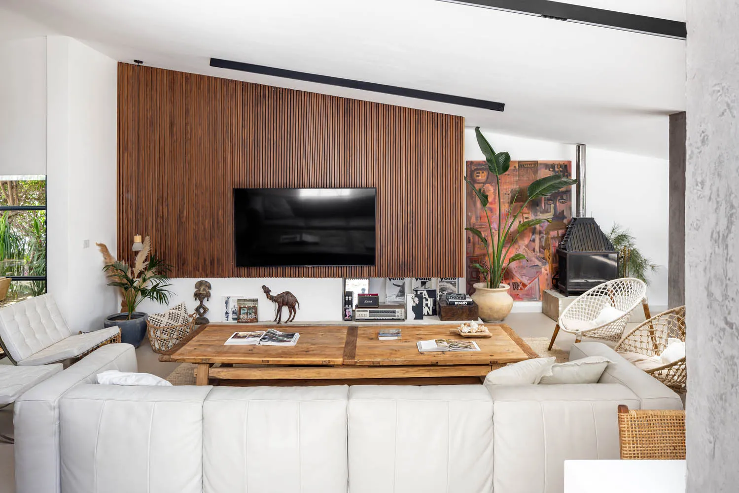 A modern industrial living room with a wooden wall, leather furniture, and a large screen TV.