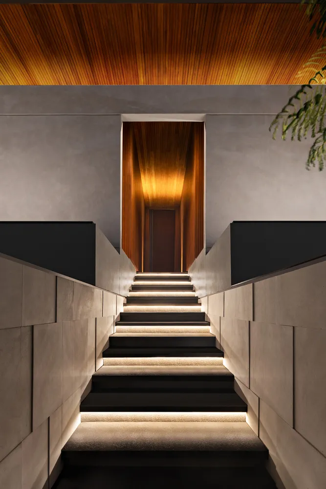 A modern interior staircase with concrete steps and illuminated risers, featuring a wooden ceiling.
