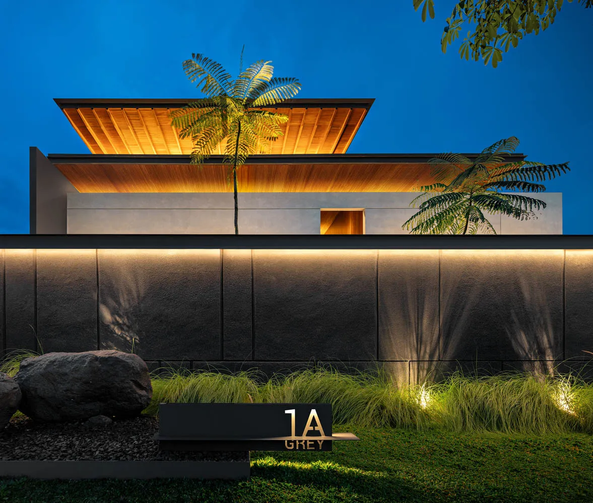 A modern property featuring a concrete exterior with illuminated lighting at dusk.