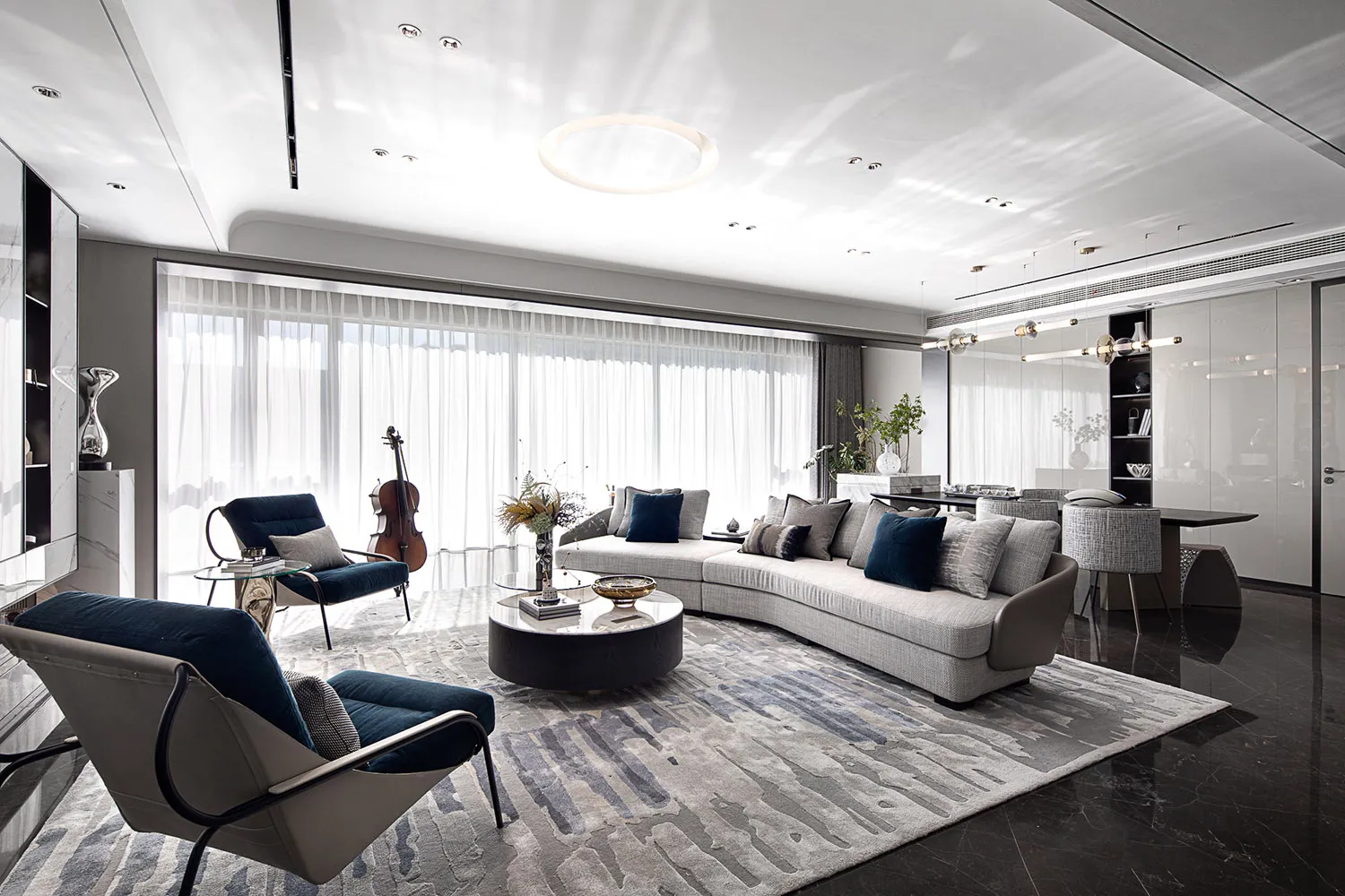 Contemporary living room with modern interior design elements, featuring a curved sofa, dark armchairs, and large windows.