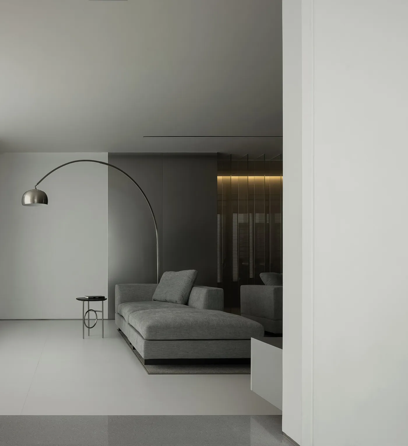 Modern living room featuring minimalist gray furnishings and a sleek, arching floor lamp.