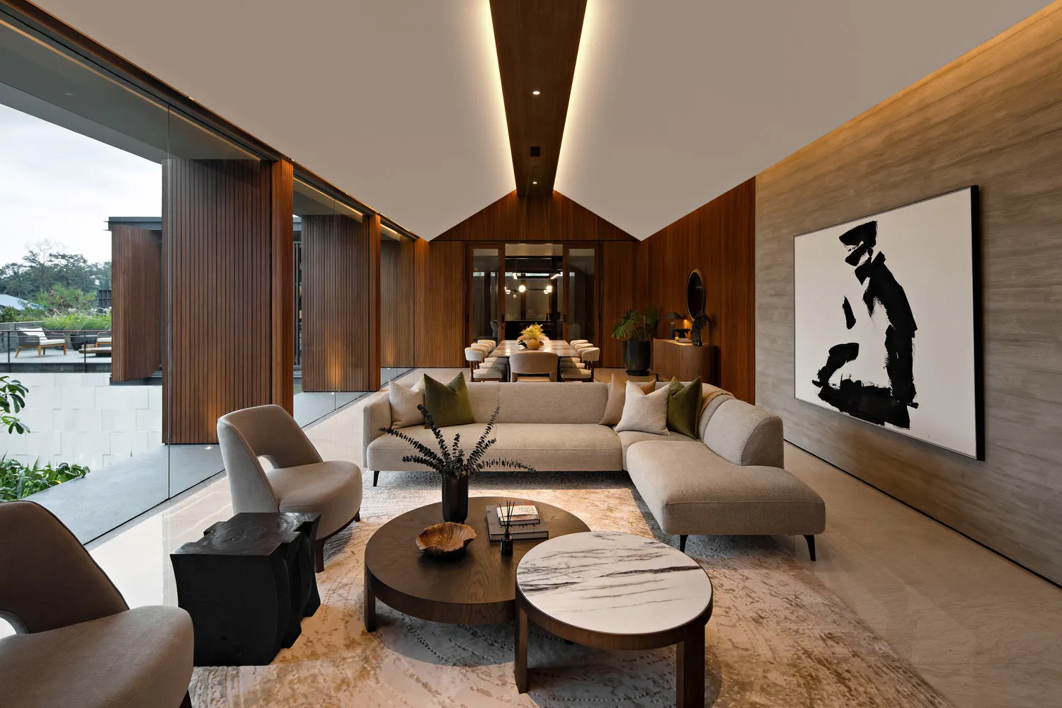 A modern living room with a wooden floor, marble coffee tables, and glass accents.