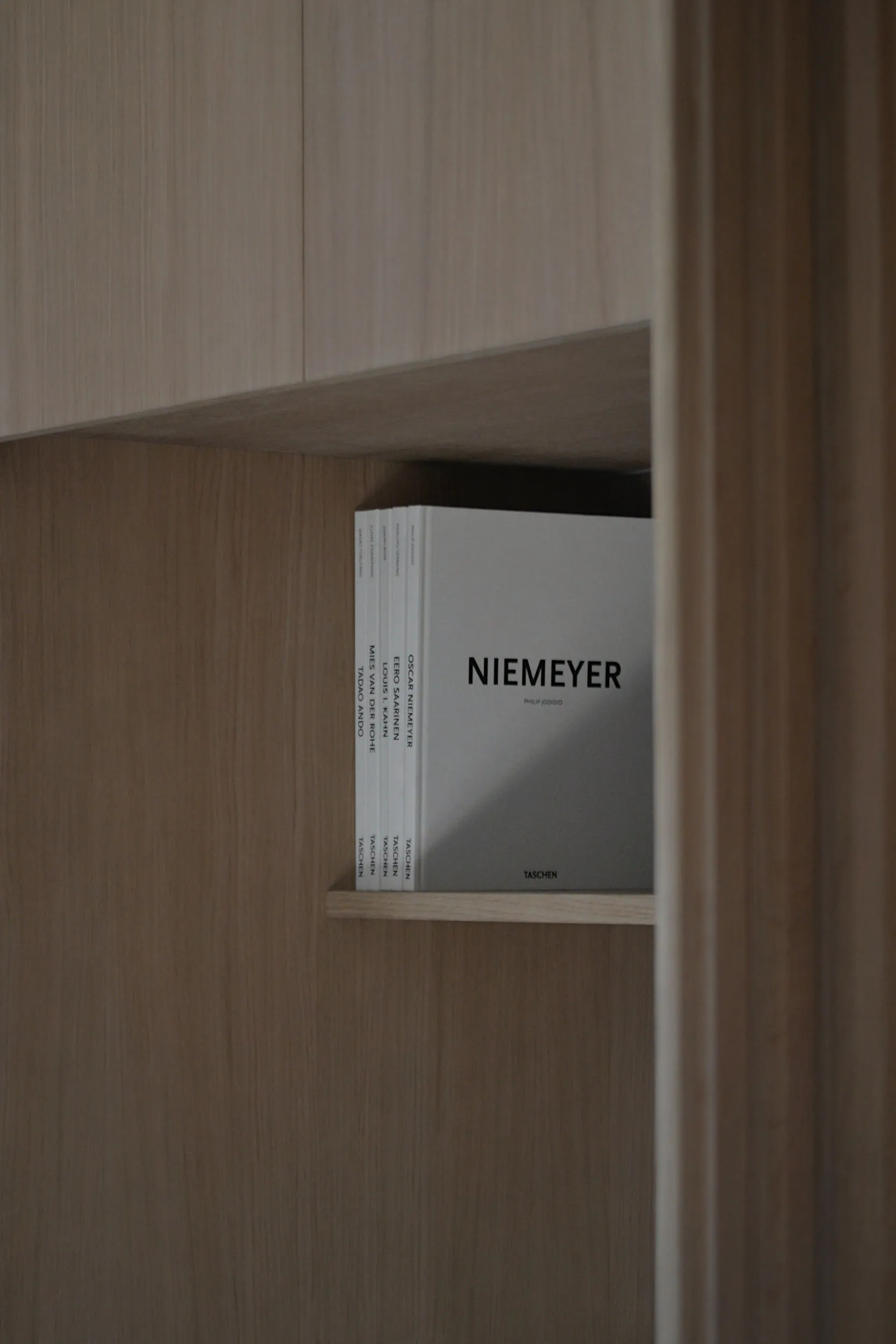 A modern minimalist bookshelf made of wood with a minimalist book titled "Niemeyer"
