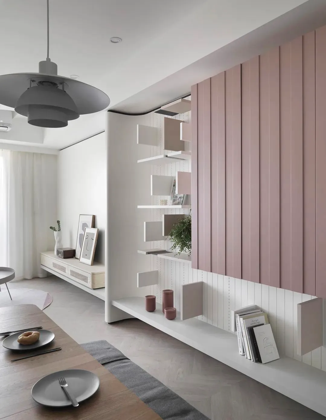 A modern minimalist living room with floating shelves, wooden flooring, and a hanging lamp.
