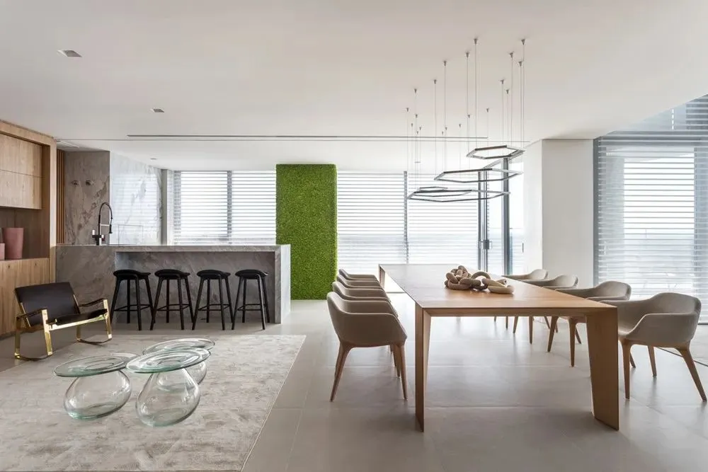 Modern residential dining room featuring wooden table, glass chairs, marble countertop, and upholstered seating.