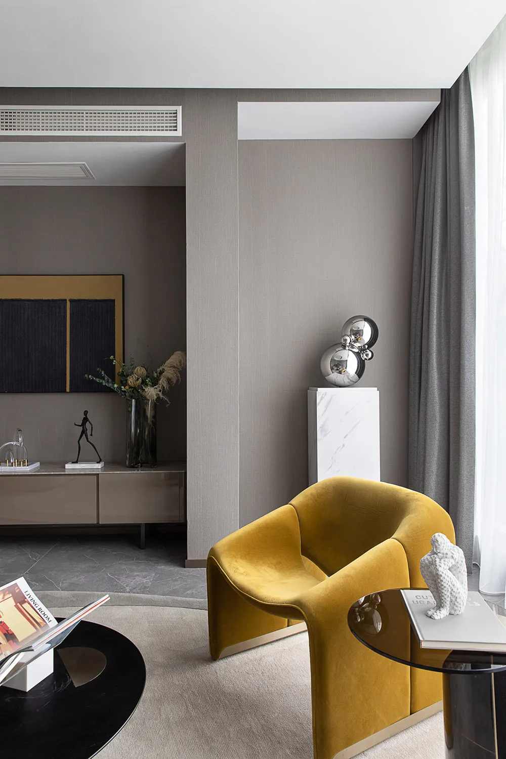 A modern living room featuring a yellow velvet armchair, side table with decorative items, and a sideboard with a vase and sc