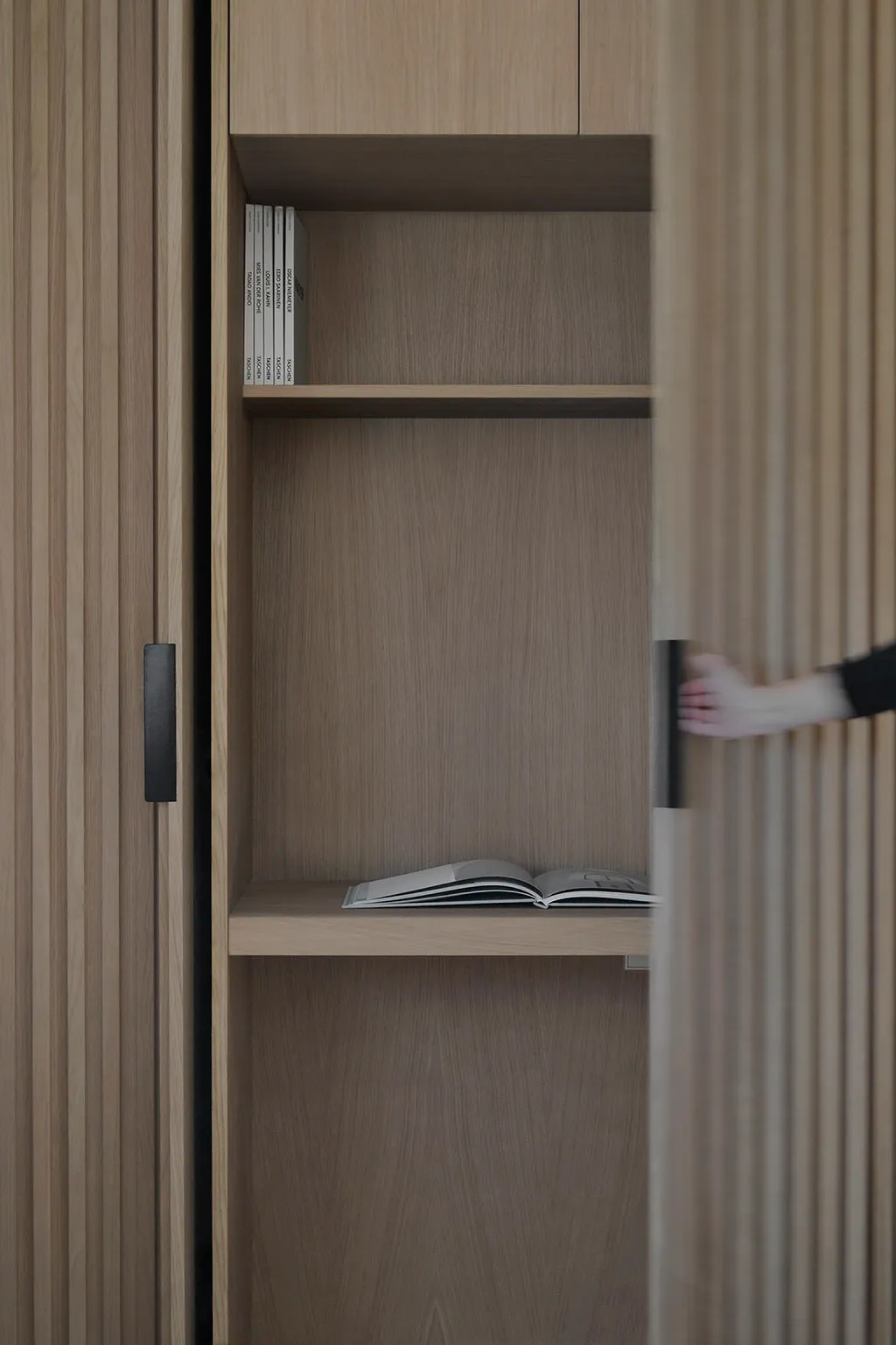 A modern interior design features a wooden shelf with books and a magazine.