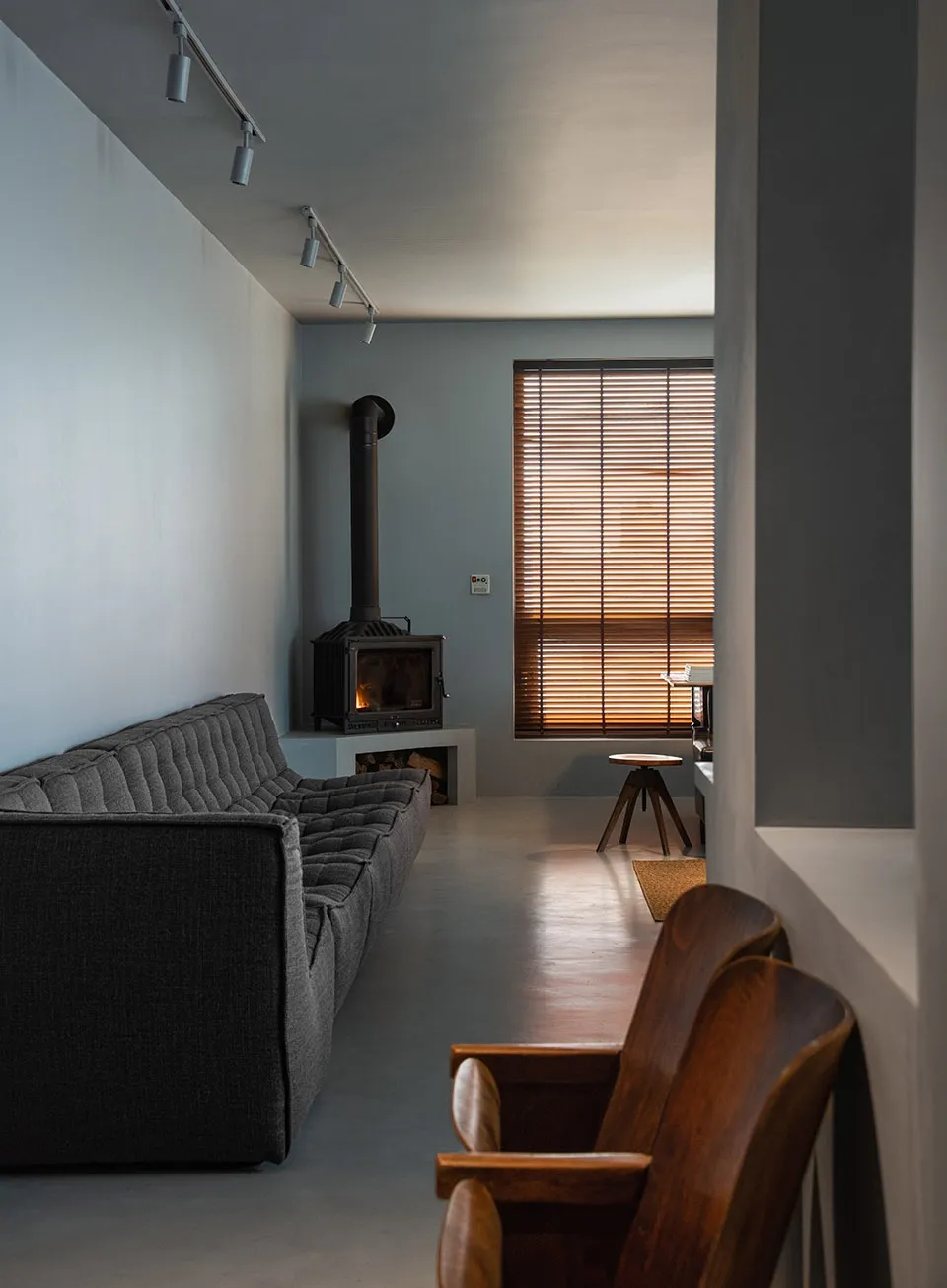 Modern living room featuring a concrete floor, fireplace, and wooden furniture.