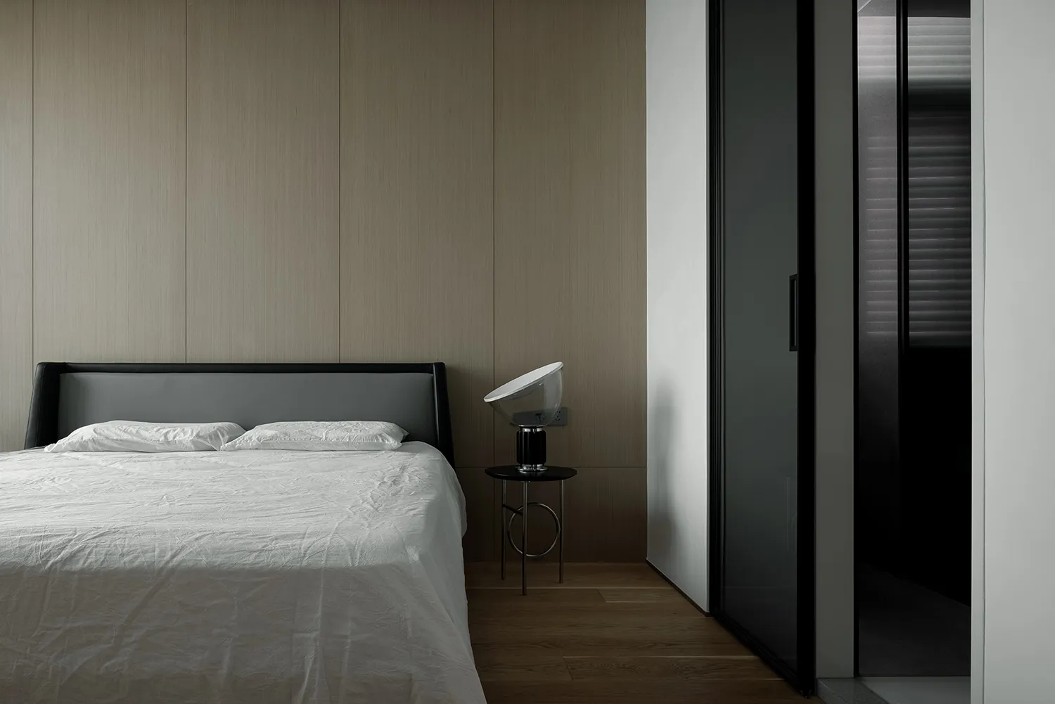 Minimalist bedroom with a wooden headboard and floor-to-ceiling wood panels.