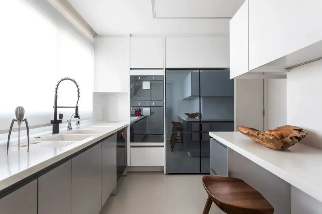 A modern kitchen with white and gray cabinets, concrete countertops, and black accents.
