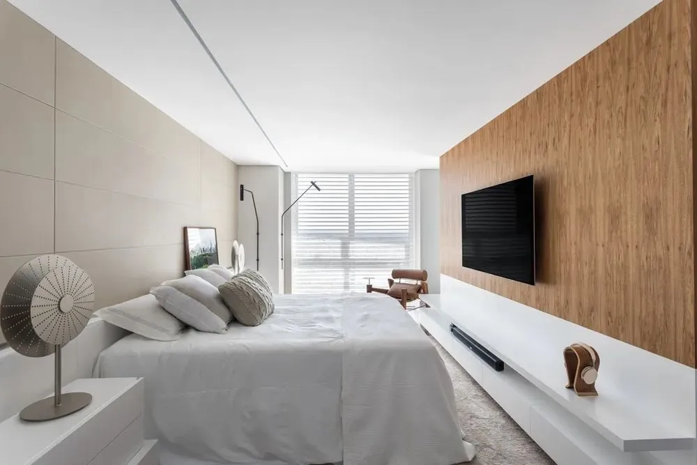 A modern bedroom with minimalist design featuring a white bed and wooden accents.