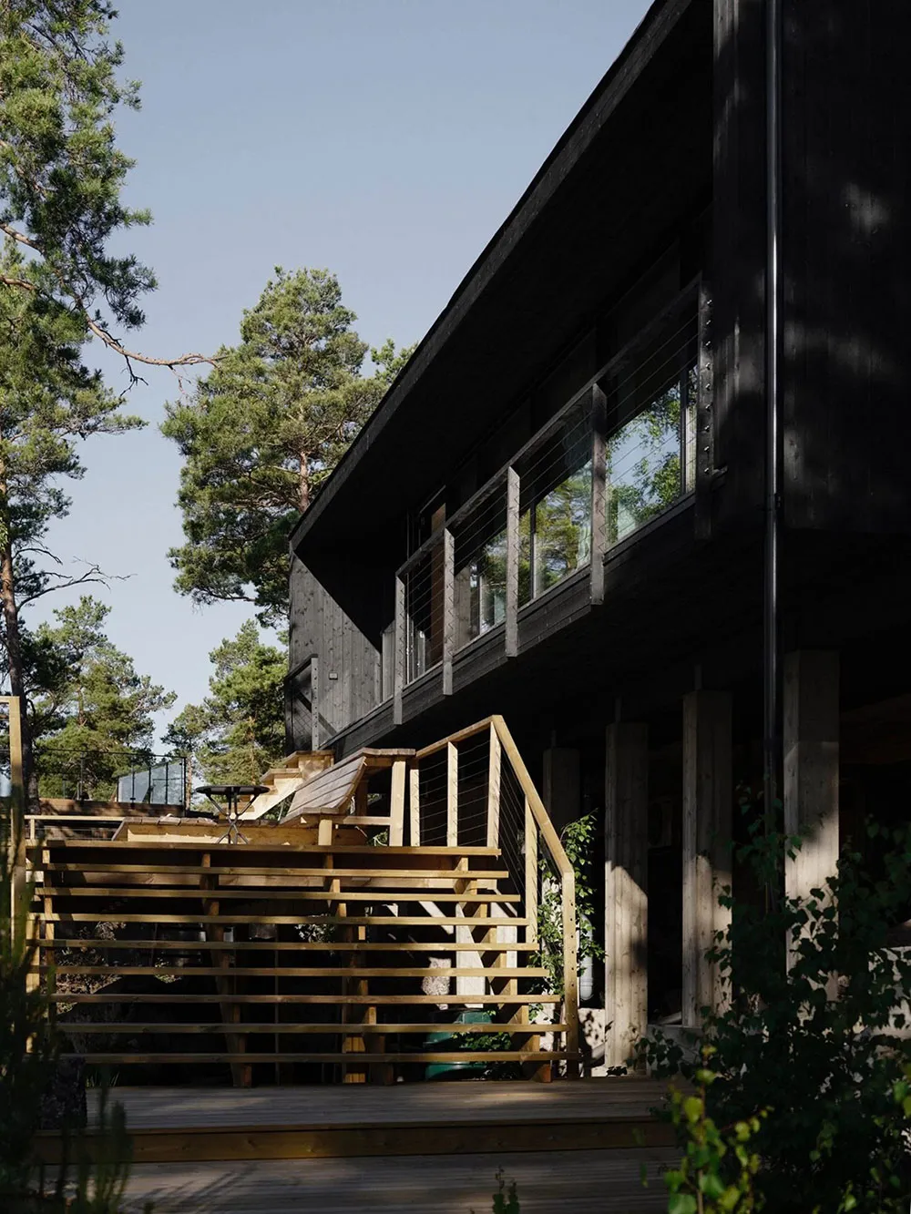 Modern minimalist residential building with wooden exterior, glass windows, and concrete foundation.