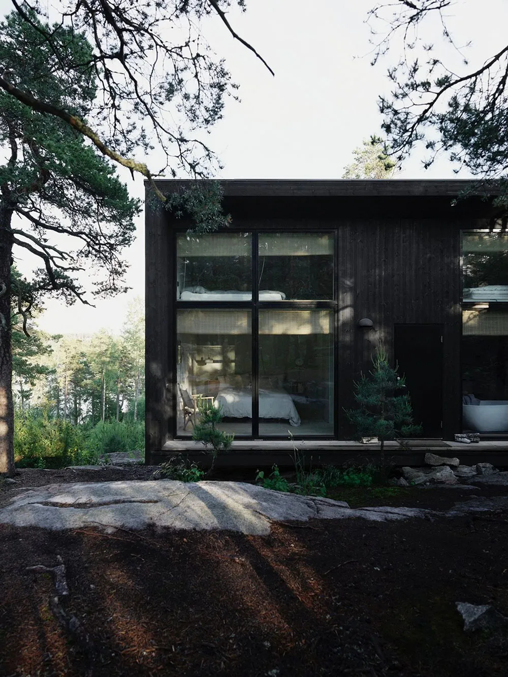 Minimalist design of a residential interior with wood finishes, featuring a bedroom with large windows and a bed.