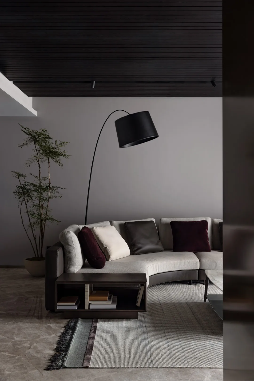Modern, contemporary living room with minimalist design, featuring a curved sofa, floor lamp, and minimalist decor.
