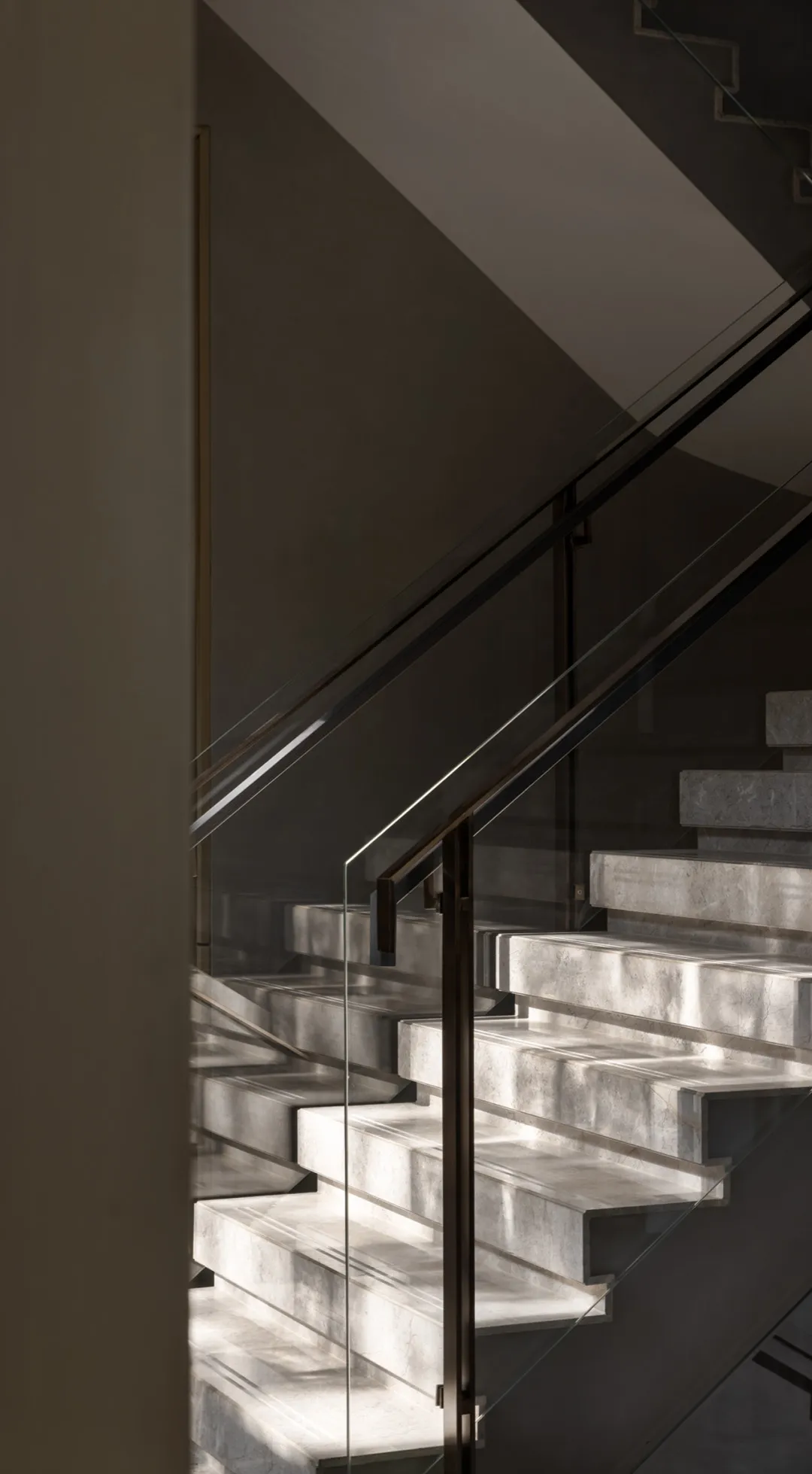 A modern marble staircase with glass railings.