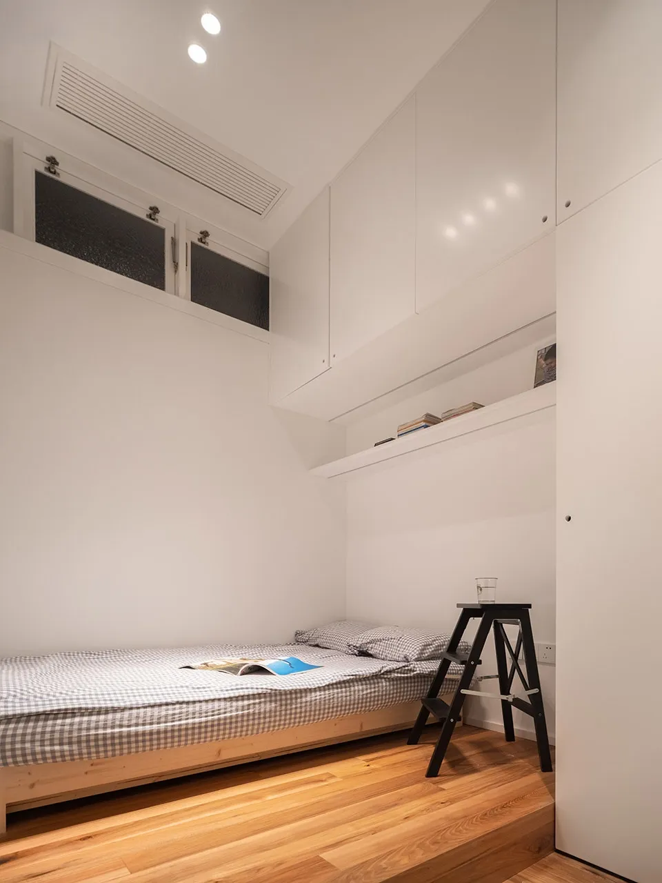 Minimalist bedroom with wooden floor, bed, and plaster walls.