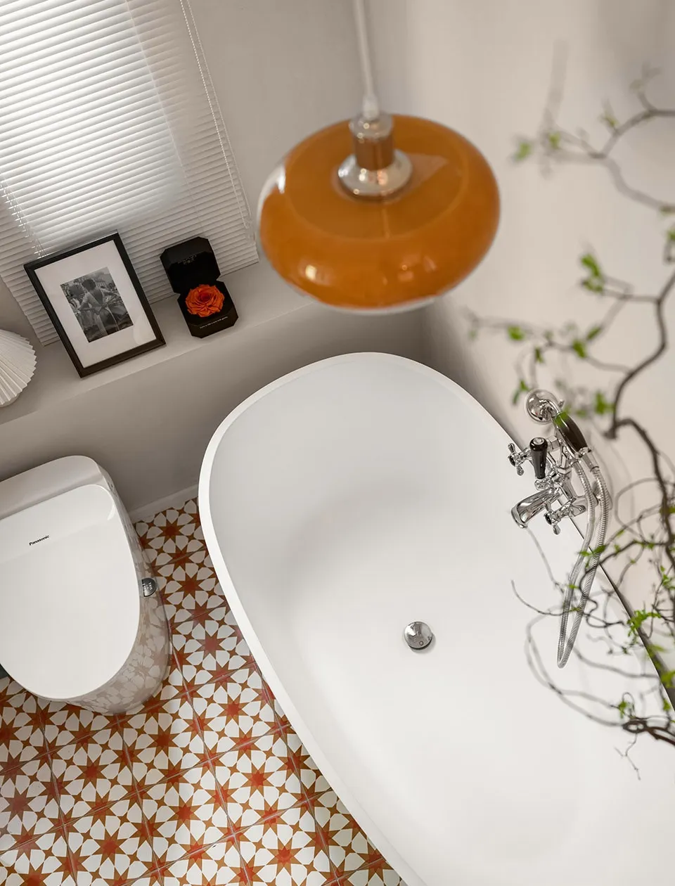 Modern bathroom featuring a freestanding bathtub, toilet, and terracotta and white porcelain tile flooring.