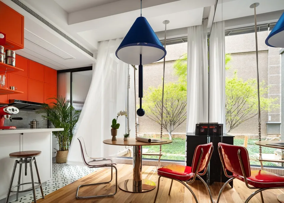 A modern kitchen with red and orange upholstered chairs