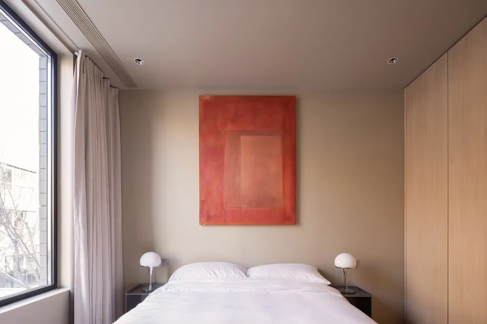 A minimalist bedroom with a large bed, two nightstands, and a large painting on the wall.