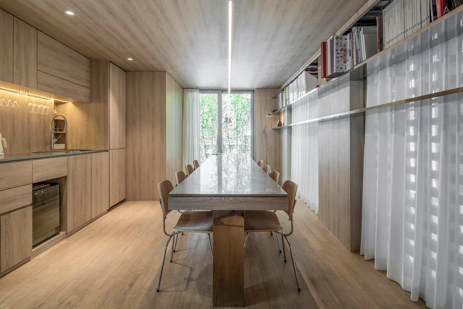A modern dining room with wooden furniture and a long table.