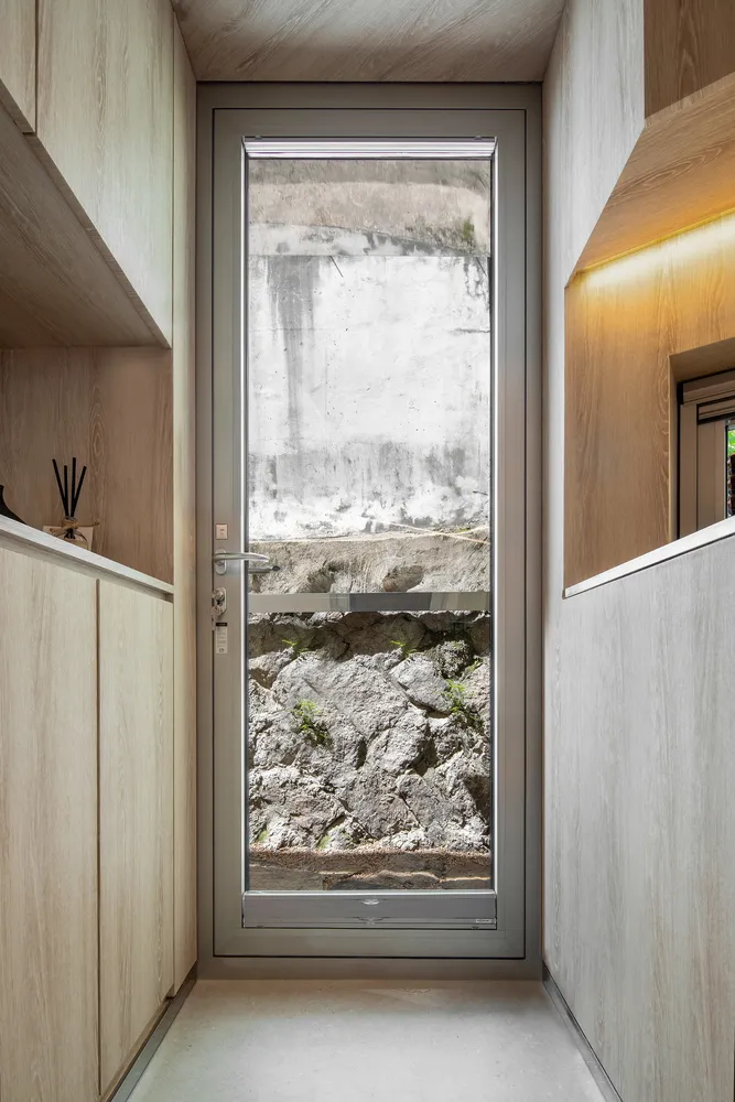 A modern interior doorway with metal and glass elements, revealing a view of concrete and rocky terrain outside.