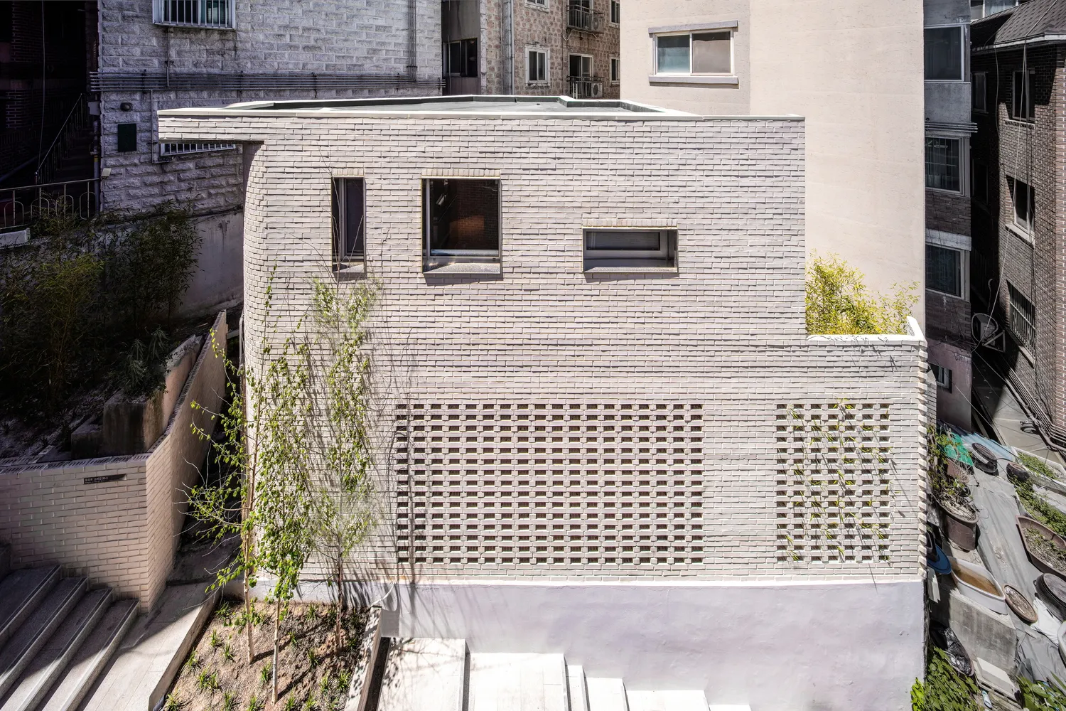 一座極簡主義建築,外牆為白色磚面,搭配大型玻璃窗與綠化屋頂花園。