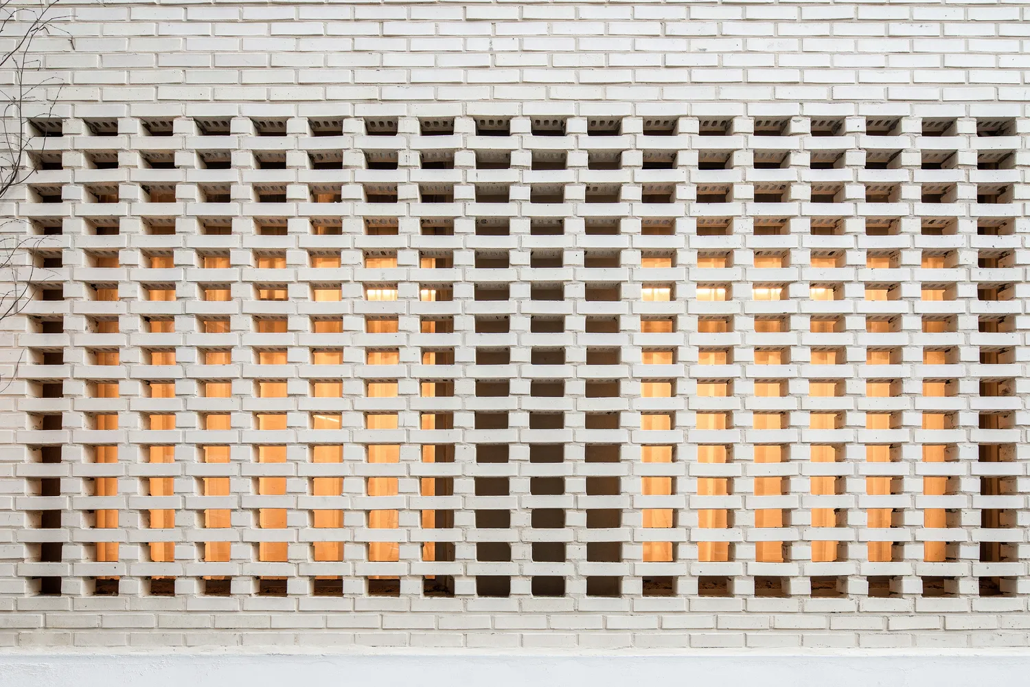 A white brick wall featuring a geometric pattern with alternating solid and transparent bricks.