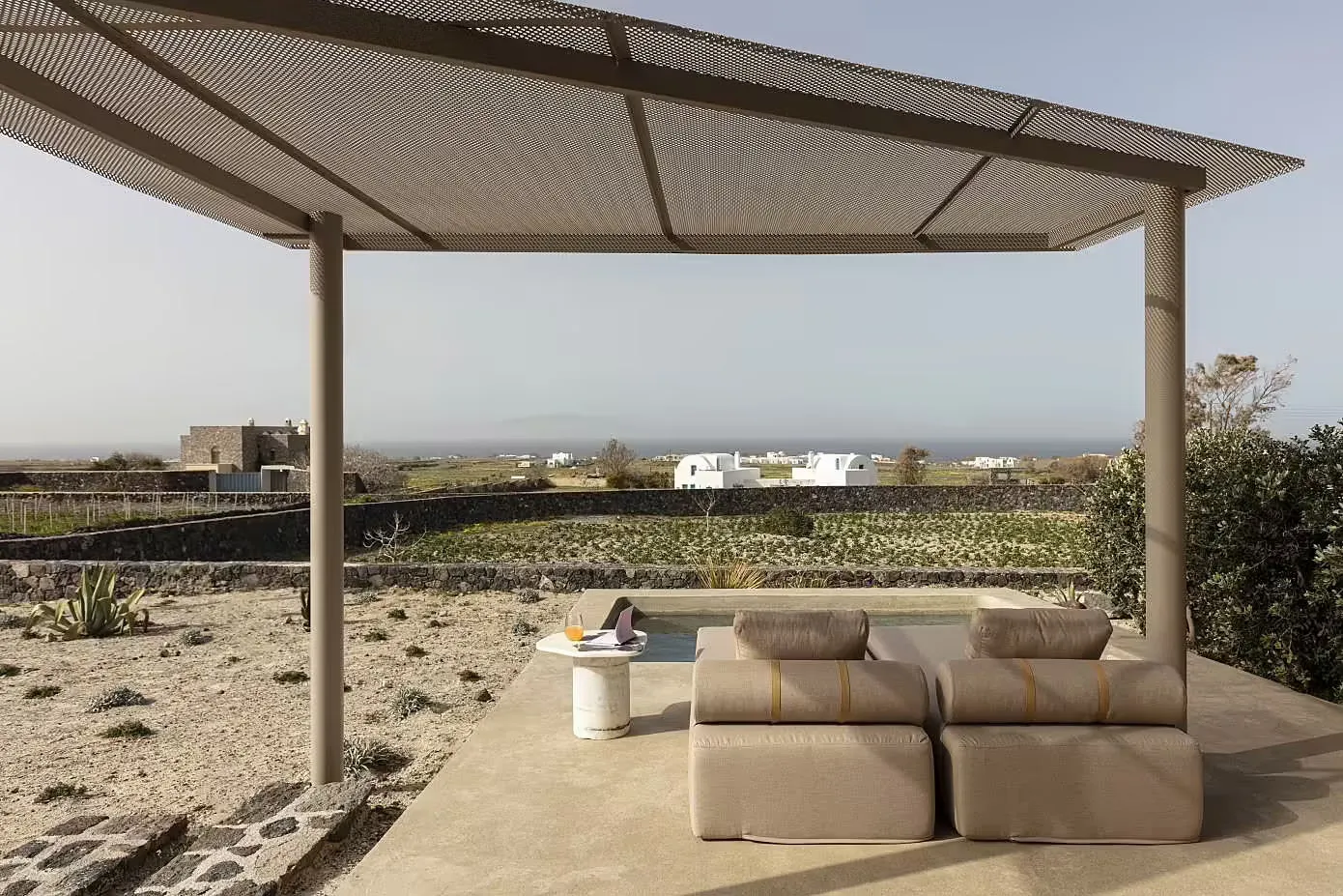 A minimalist outdoor lounge area with a concrete structure and seating, overlooking a scenic landscape.