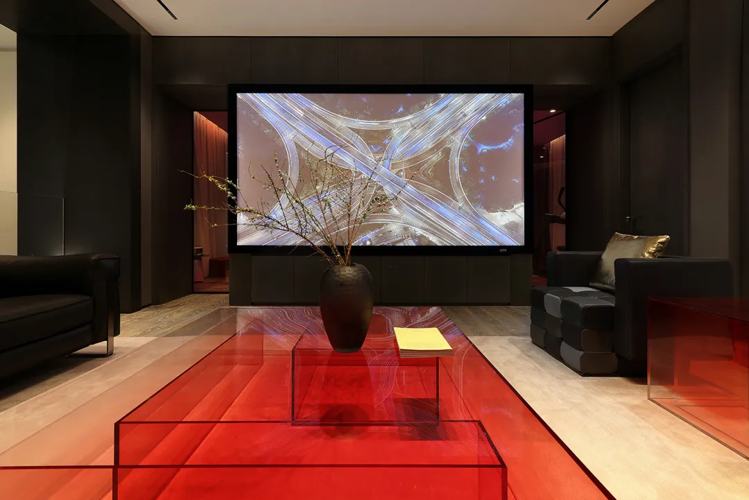 Modern living room featuring a glass table with a red tablecloth, a large screen displaying a complex network of roads, and b