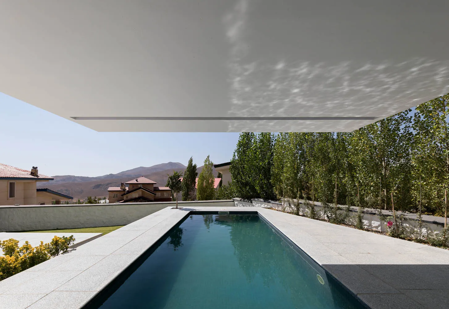 Modern luxury villa featuring a concrete and glass exterior with a swimming pool.