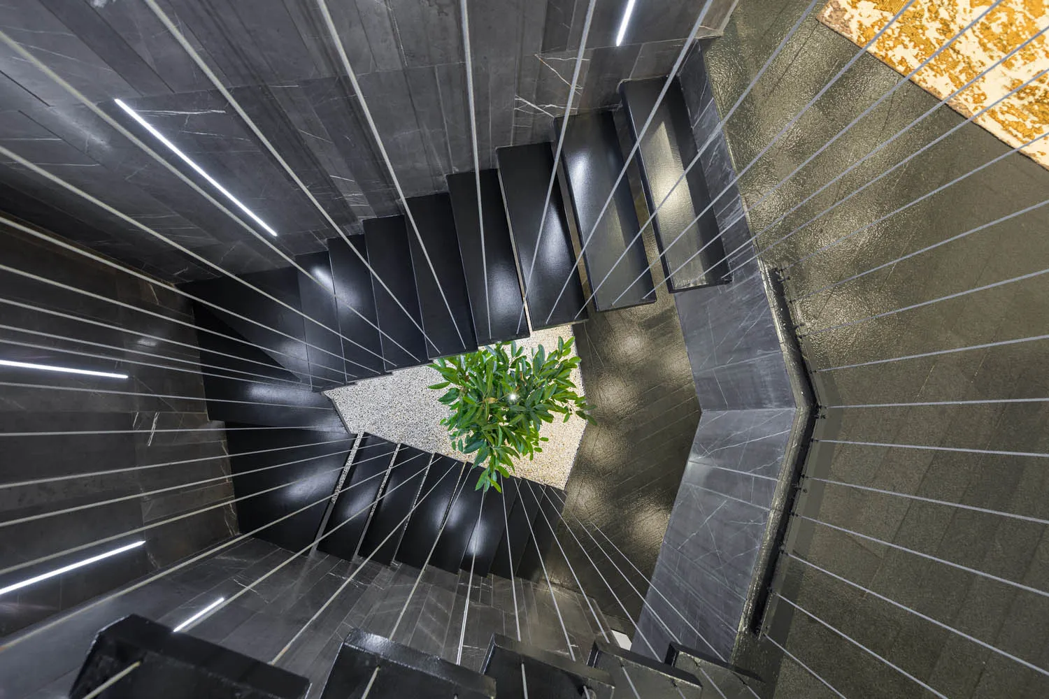 A modern staircase with black metal railings and marble steps and flooring.