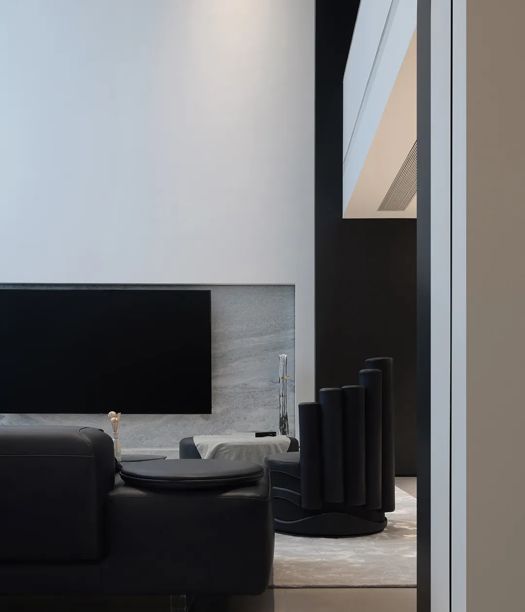 Modern living room featuring black leather furniture and sleek technology elements.