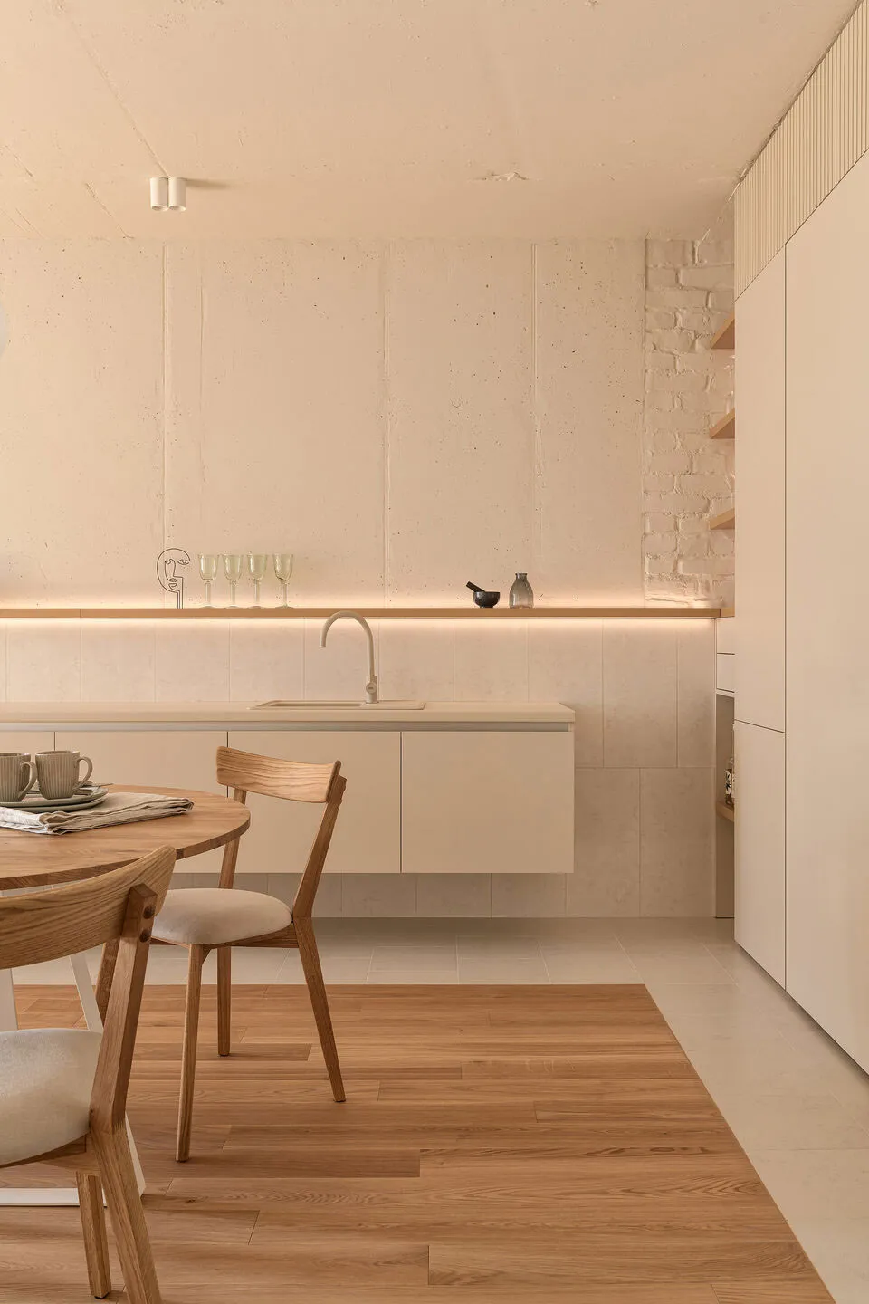 Modern minimalist kitchen featuring concrete walls, stone countertops, and wooden flooring.