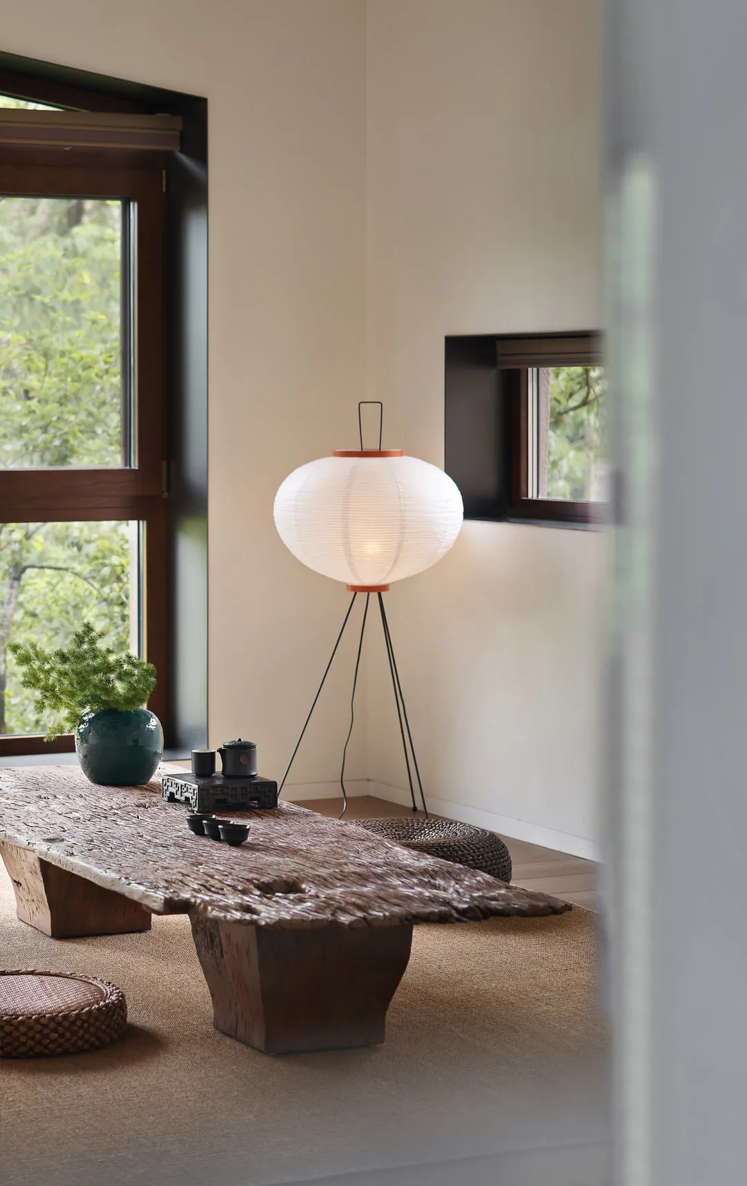 A minimalist living room featuring a wooden table, lamp, and green plant.