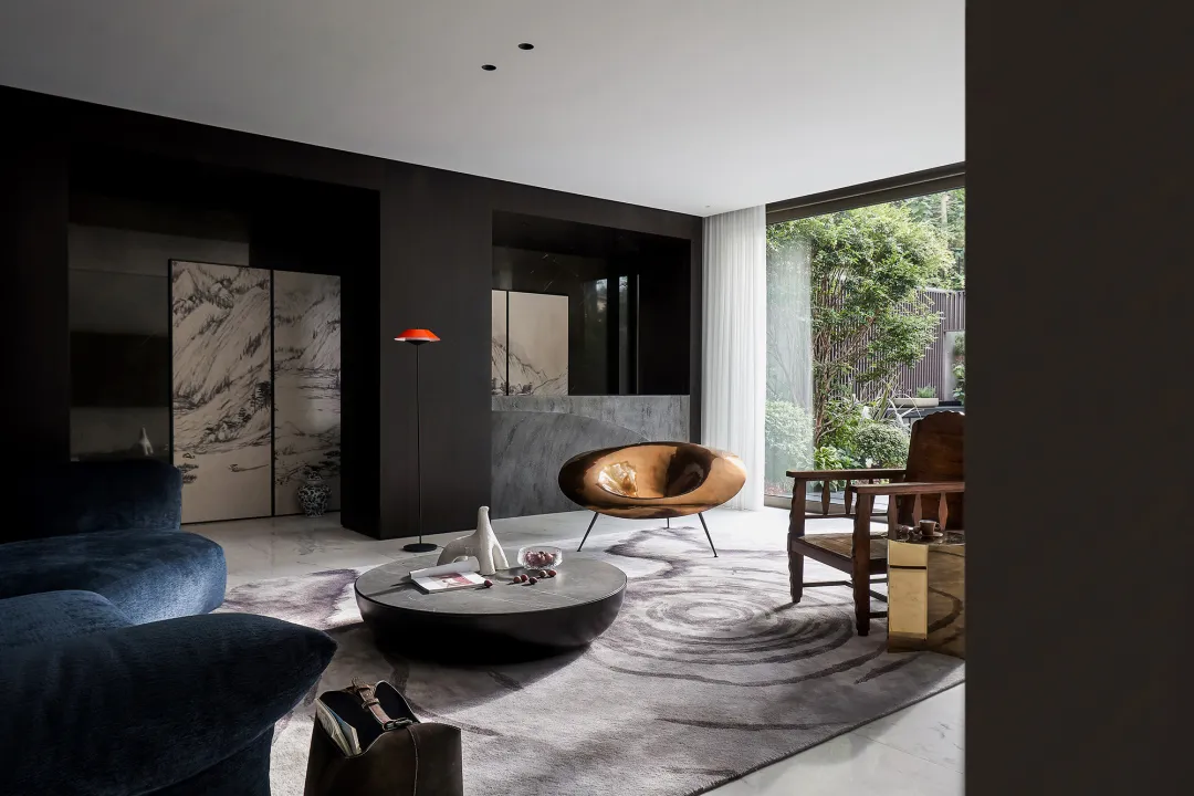 Modern living room featuring a sleek, curved wooden armchair, a round coffee table, and a dark, textured sofa, with large win