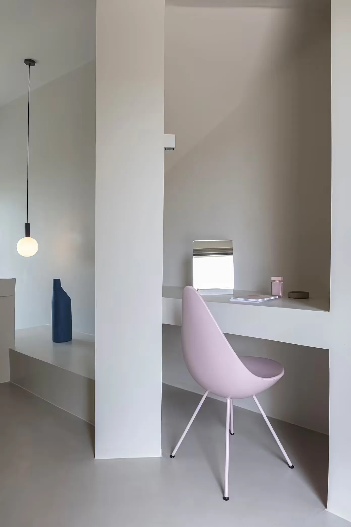 Modern minimalist home office with concrete desk, metal chair, and floating shelves.