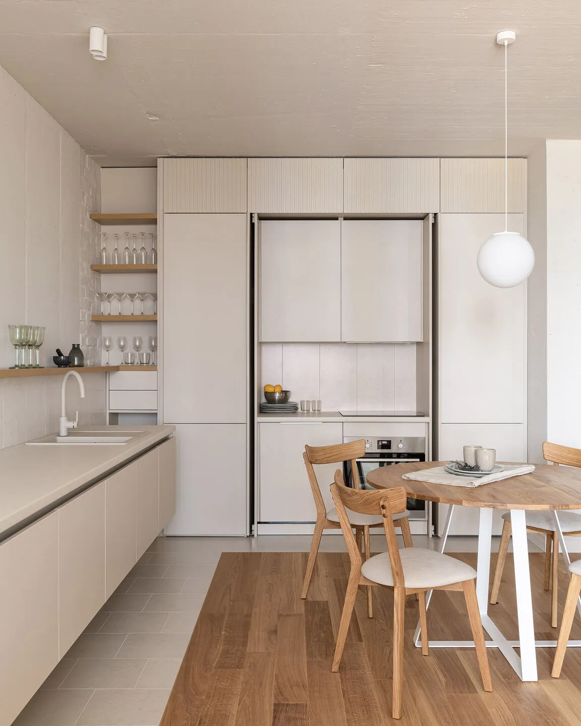A modern minimalist kitchen with light wooden furniture and clean, sleek appliances.