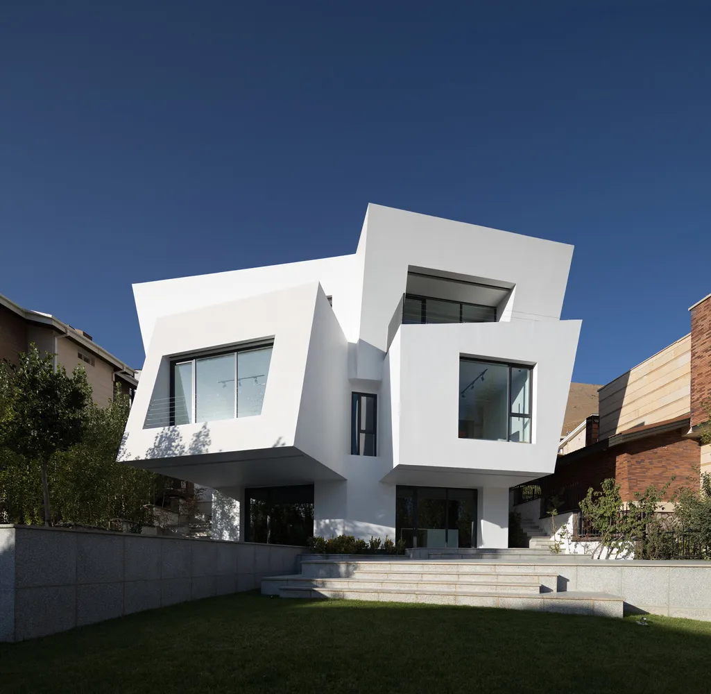 A minimalist, modern residential building featuring white concrete and glass exteriors.