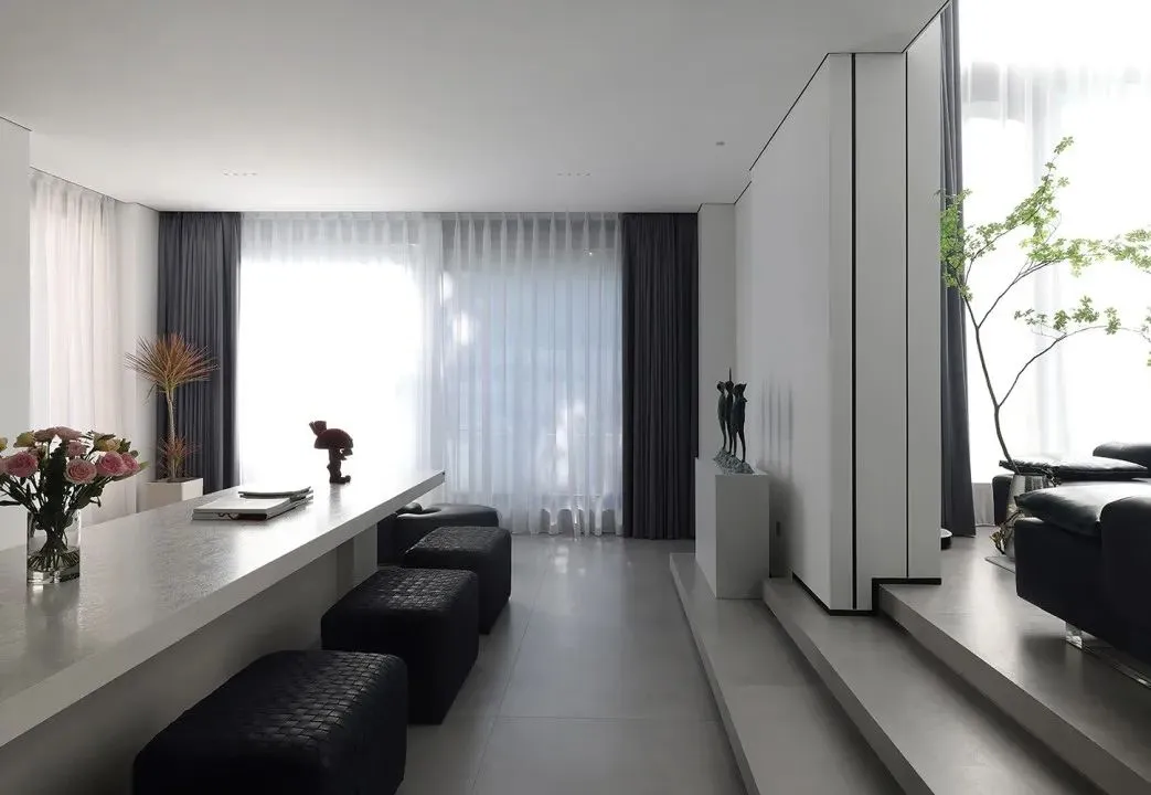 Modern minimalist living room with concrete floor and white walls.