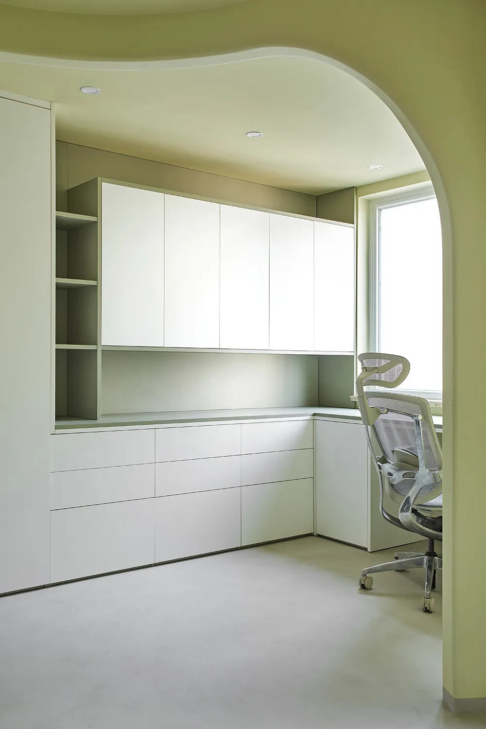 A minimalist home office featuring white cabinets.