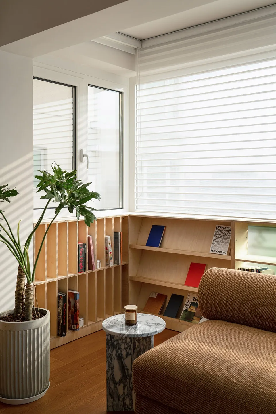 Modern living room featuring a wooden bookshelf with books and plants.