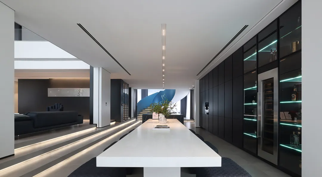 A sleek, modern dining room with minimalist design, concrete floors, glass walls, and black accent walls.