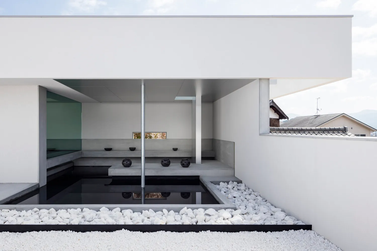 Minimalist residential interior with concrete surfaces and a serene water feature.