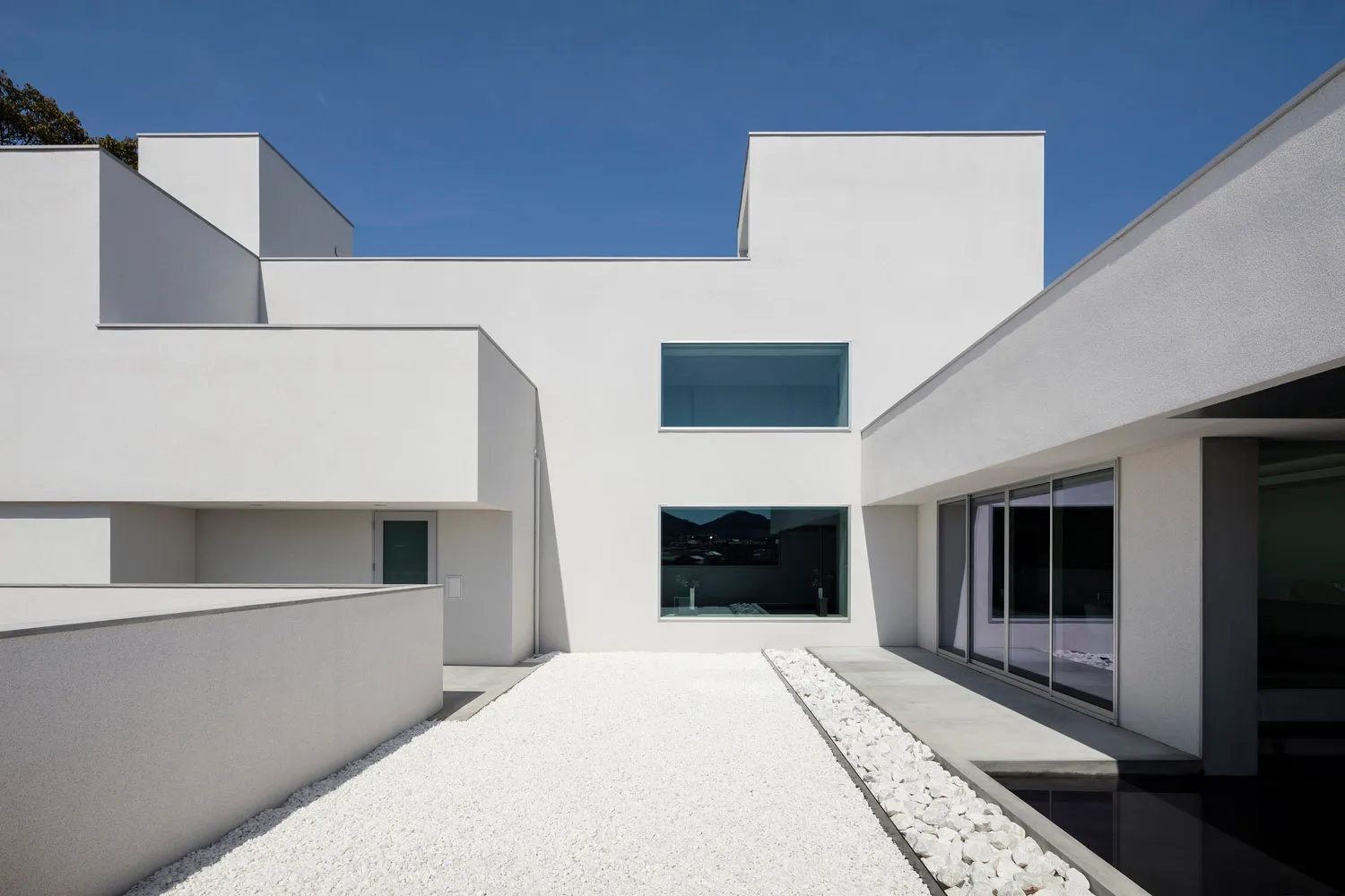 A minimalist white modern building with concrete and glass materials.