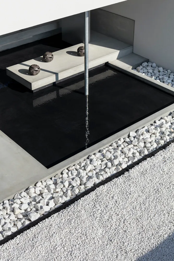 Minimalist modern architectural water feature with stone border.