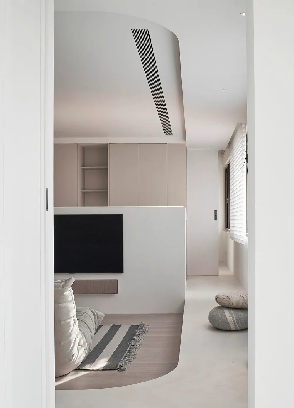 Modern minimalist living room featuring concrete walls and floor, minimalist furniture, and a sleek black TV console.