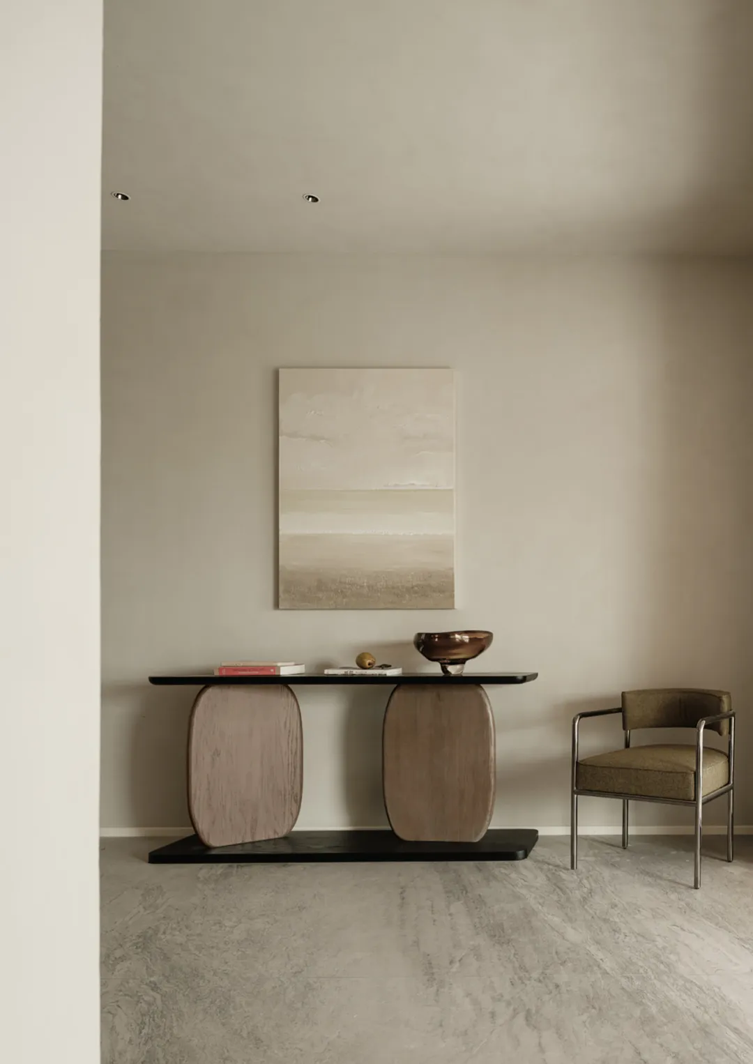 A minimalist living room featuring a console table with organic-shaped wood columns, a black tabletop, and a single brown cha