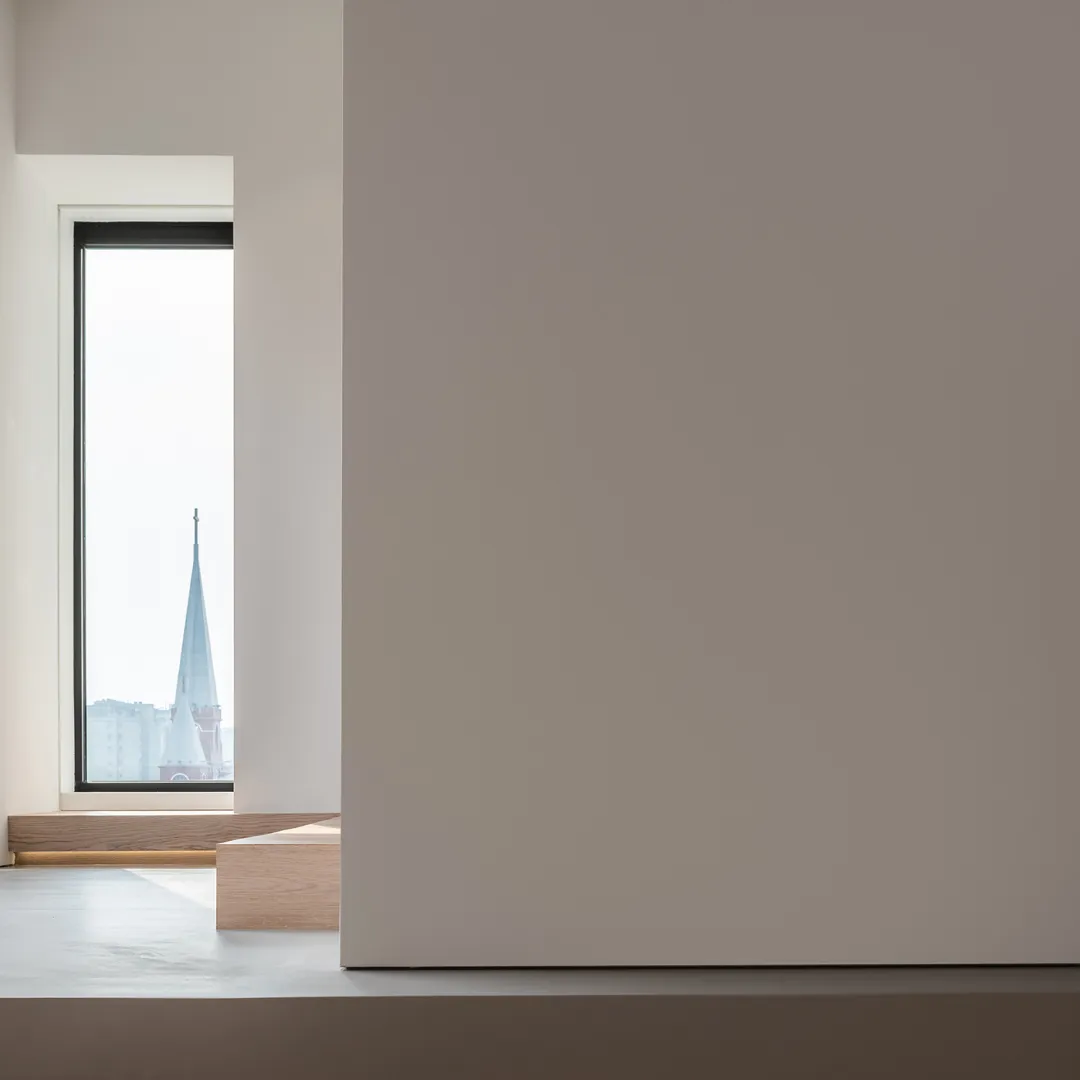 A minimalist window view of a church spire in an indoor setting.